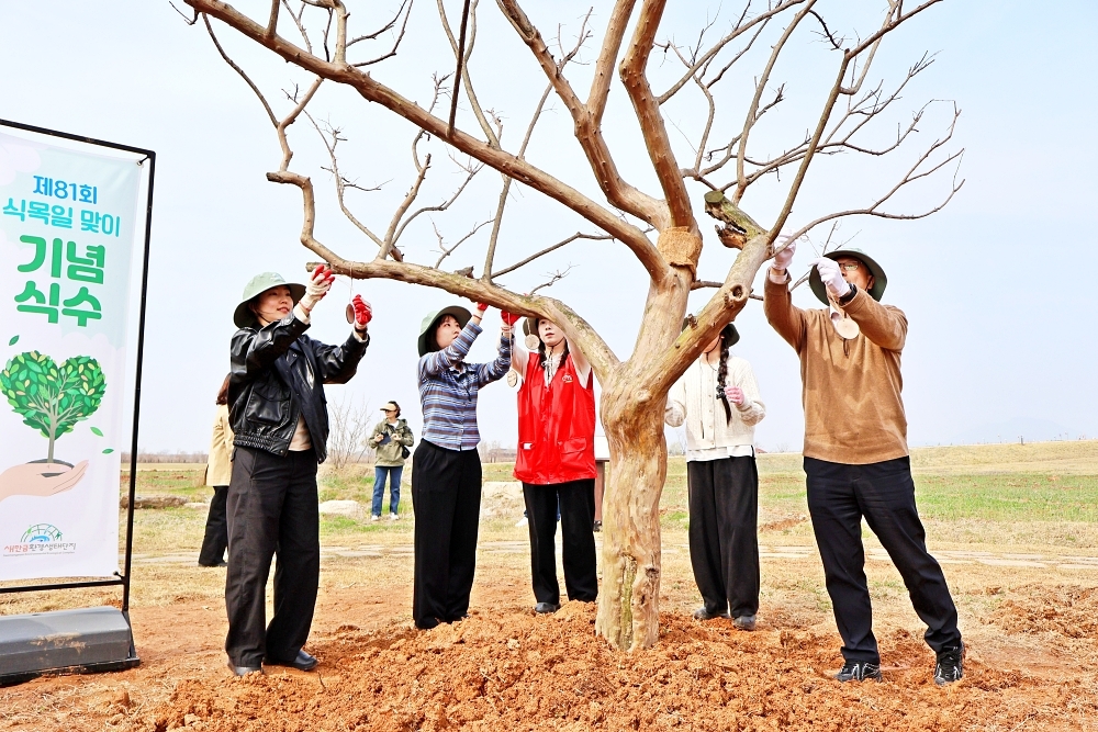 하림 임직원 및 행사 참여자들이 새만금환경생태단지에 나무를 심고 친환경 소재를 활용해 제작한 수목 이름표를 나무에 직접 걸어주고 있다. 하림 제공