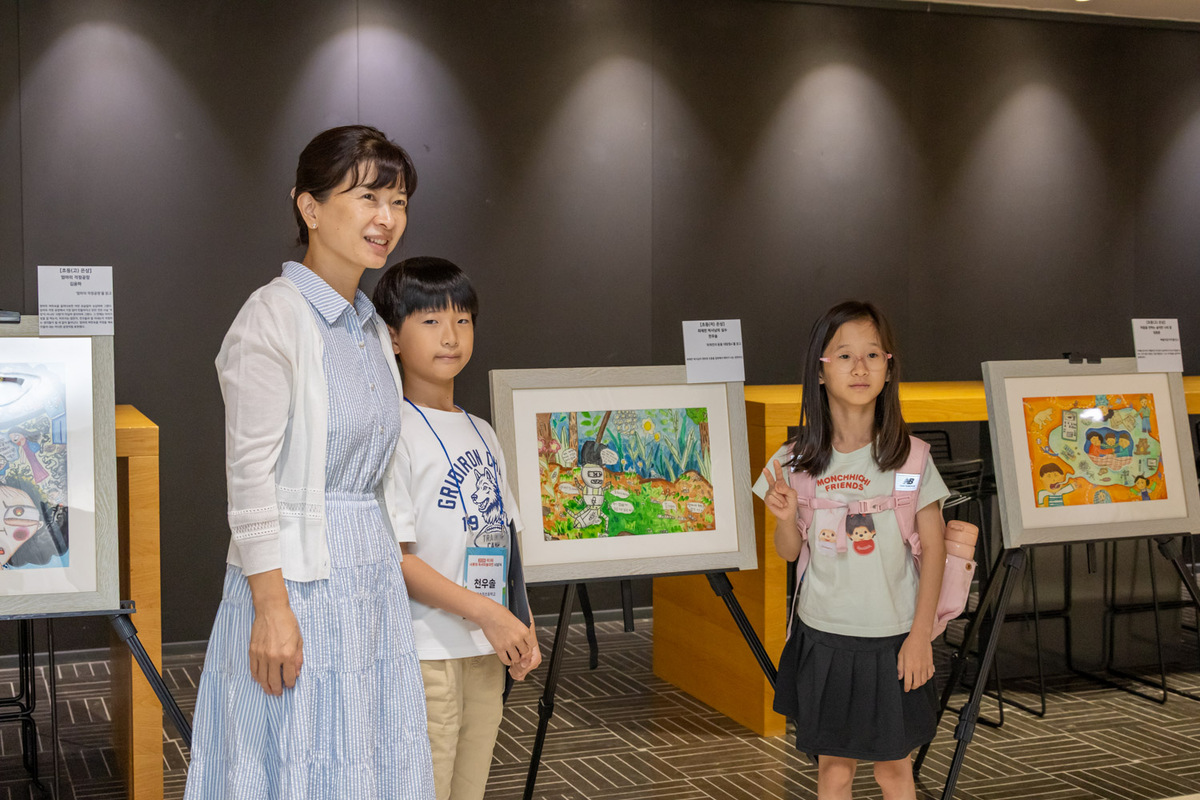 제3회 샤롯데 독서미술대전 수상자 어린이가 작품 앞에서 가족과 기념사진을 찍고 있다. 롯데장학재단 제공