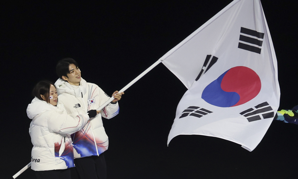 대한민국 국가대표 선수단의 피겨 차준환, 스피드스케이팅 김민선이 2026 밀라노·코르티나 담페초 동계올림픽 개막식에서 태극기를 흔들며 입장하고 있다.