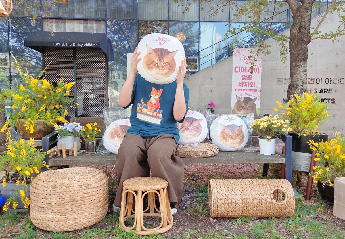 디어레이 벚꽃 바자회 방문객이 ‘관식이 쿠션’을 들고 기념사진을 찍고 있다. 박재림 기자